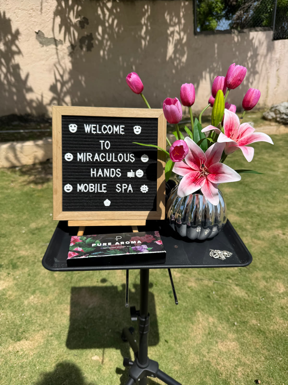 Welcome sign, pink flowers and oils prepared outdoors for mobile spa Jamaica services